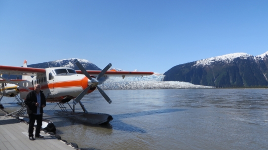 Mani with plane on Taku River. The Hole in the Wall Glacier was named when it could only be seen through the gap in the hills, which it has now advanced through.